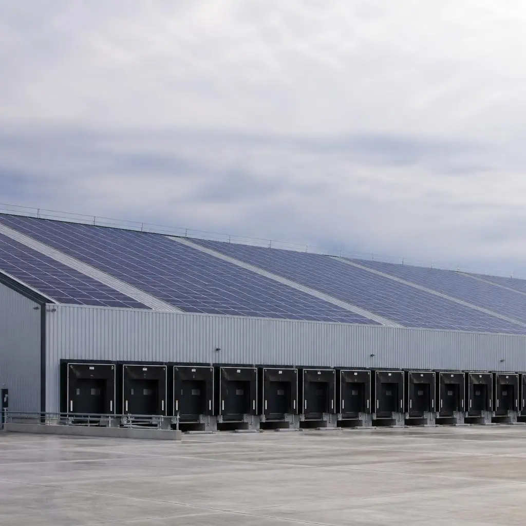Solar panels across a large warehouse roof beneath a clear sky
